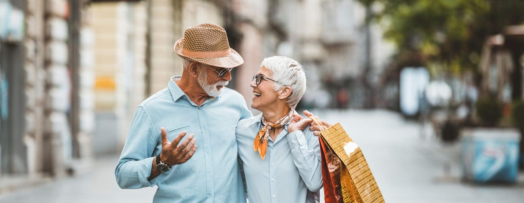 a man and woman holding shopping bags while walking
